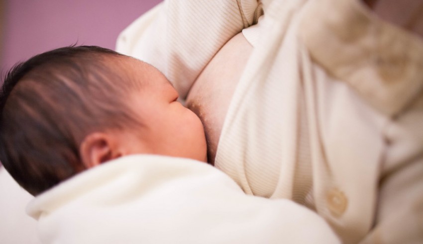 A baby is being breastfed by a woman.