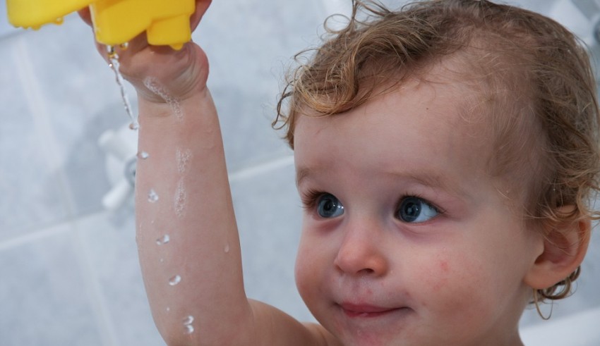 A child is holding a yellow duck toy.