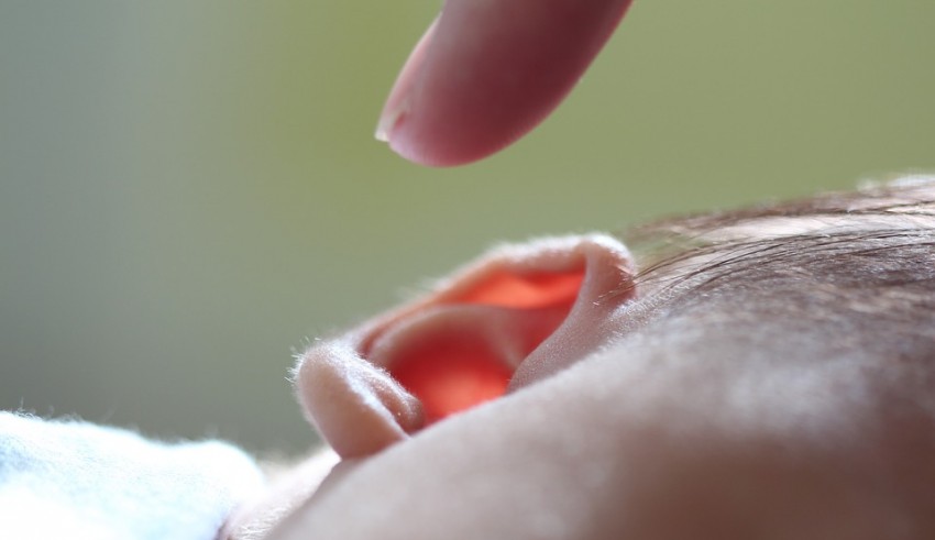 A baby's ear is being touched by a finger.