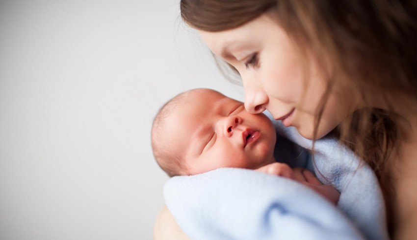 A woman kisses her newborn baby.