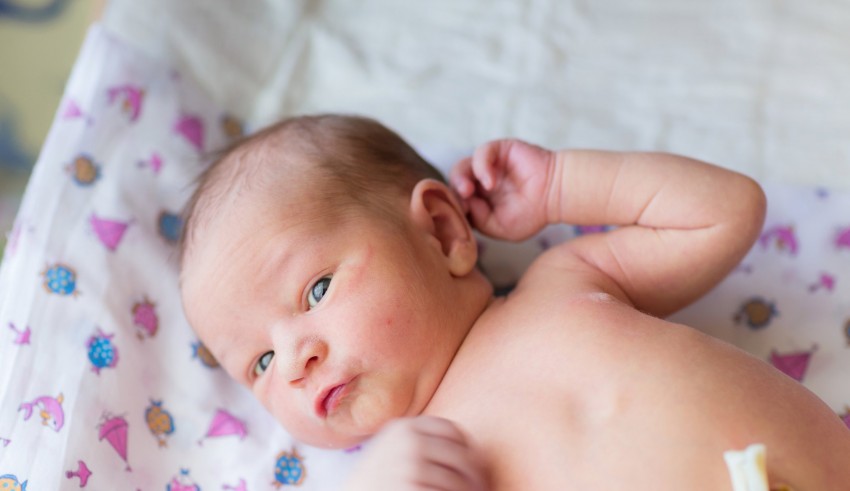 A newborn baby is laying on a bed.