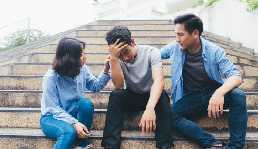 Three young people sitting on the steps of a building.