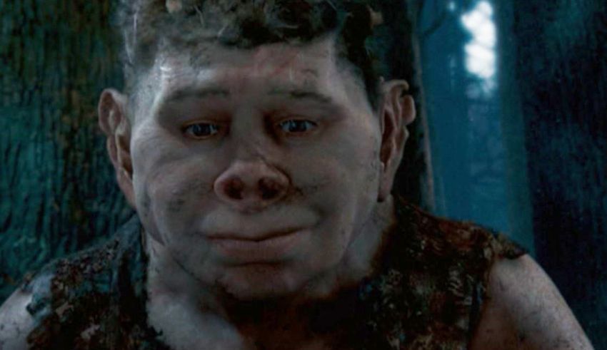 A man in a troll costume is standing in a wooded area.