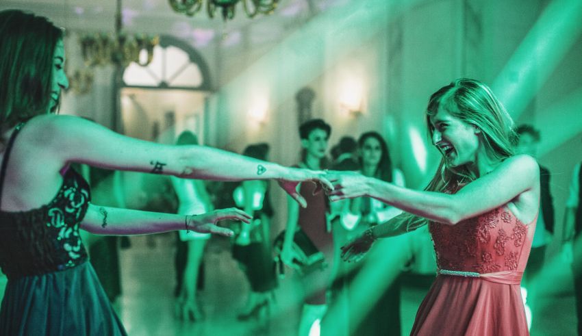 Two women dancing at a party with green lights.