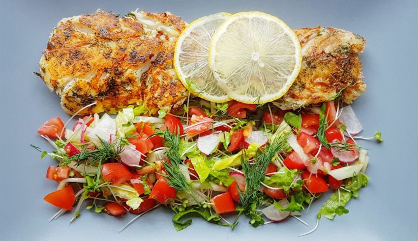 Grilled chicken with salad and lemon on a plate.