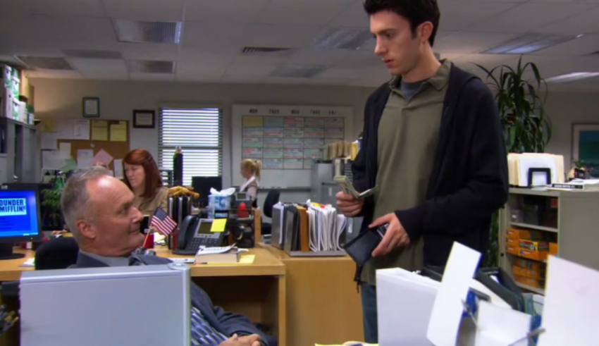 Two men in an office talking to each other.
