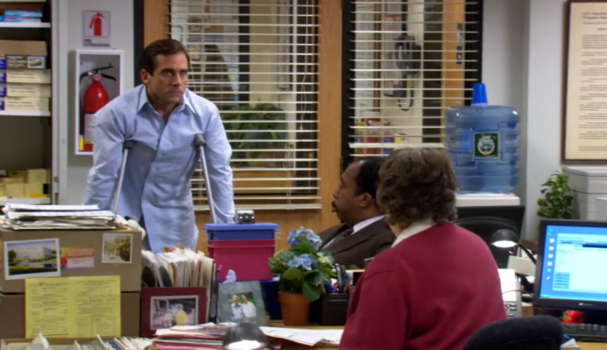 A man is standing in front of a desk in an office.