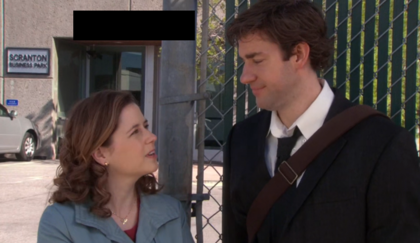 A man and woman standing next to each other in front of a fence.