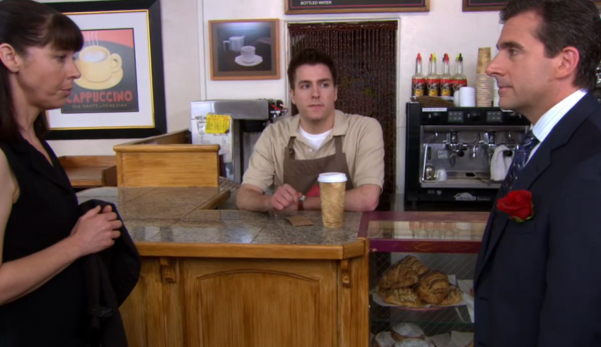 A man in a suit is talking to a woman at a coffee shop.