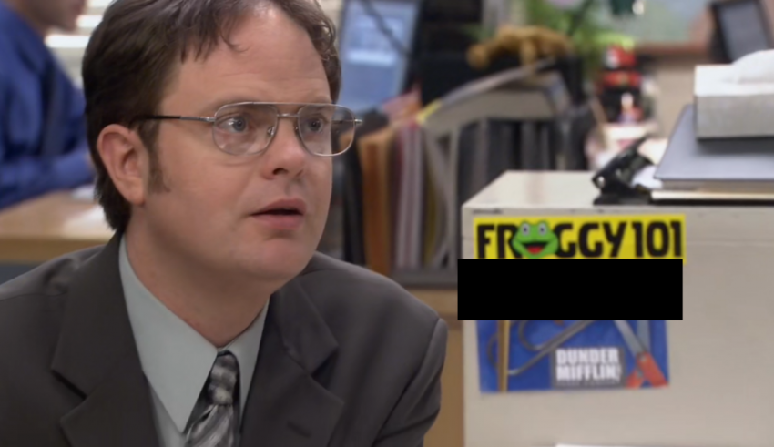 A man sitting in an office with a sign on his desk.