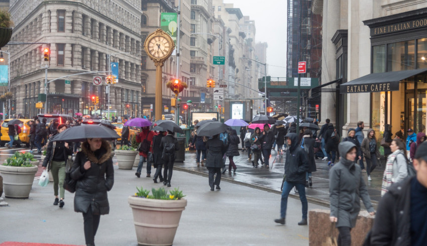 A group of people walking down a city street with umbrellas.