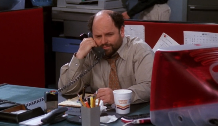 A man sitting at a desk talking on the phone.