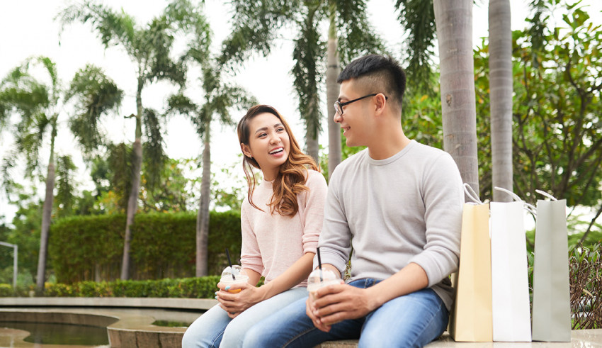 A man and woman sitting on a bench with shopping bags.