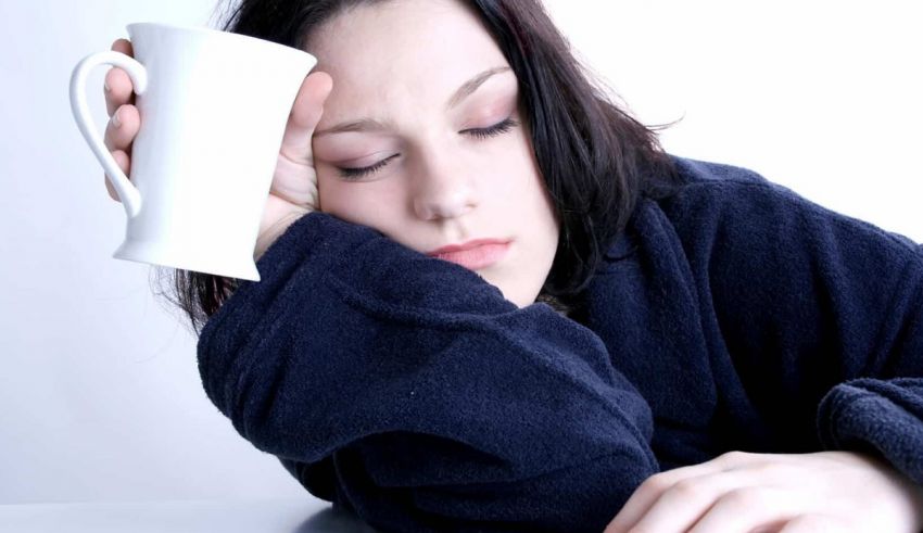 A woman sleeping with a cup of coffee.