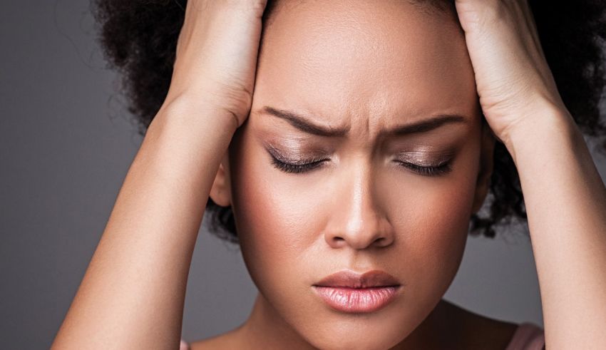 A woman is holding her head with her hands.