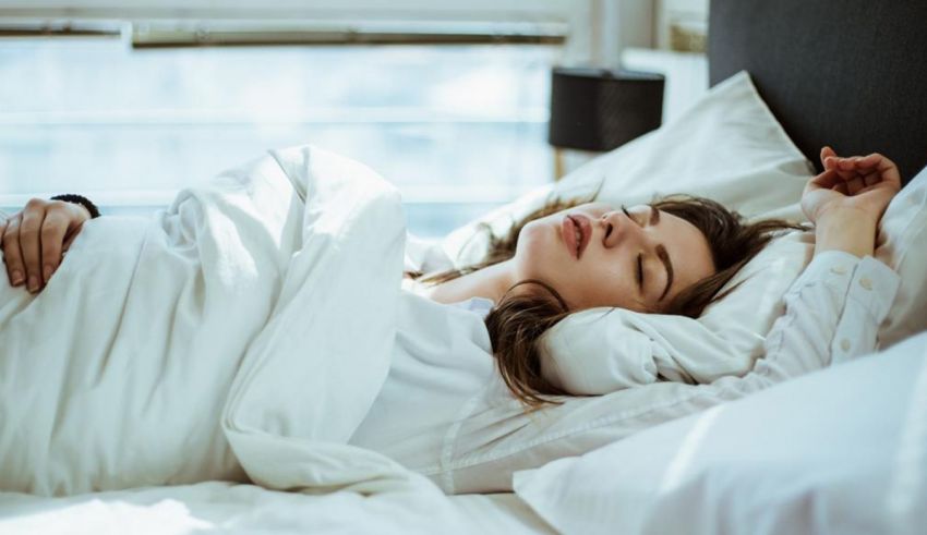 A woman sleeping in a bed with white sheets.