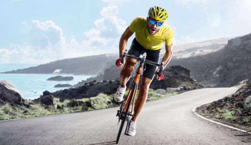 A man riding a bicycle on a road near the ocean.
