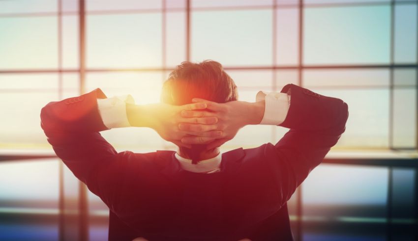 A businessman with his hands up in front of a window.