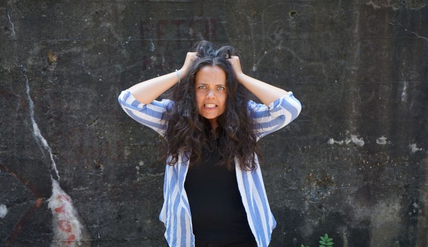 A woman holding her head up in front of a wall.