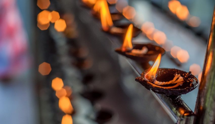 A group of lit candles on a metal railing.