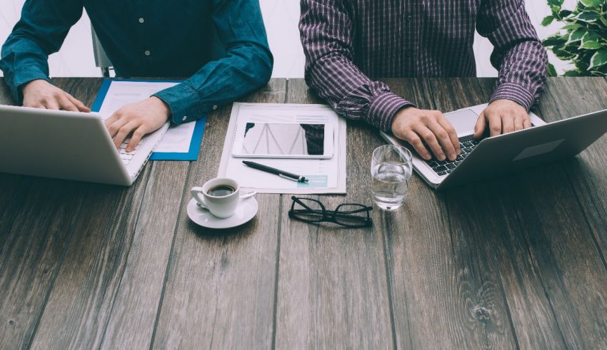 Two men working on laptops at a table.