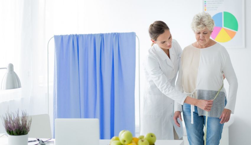 A doctor is measuring an elderly woman's waist.