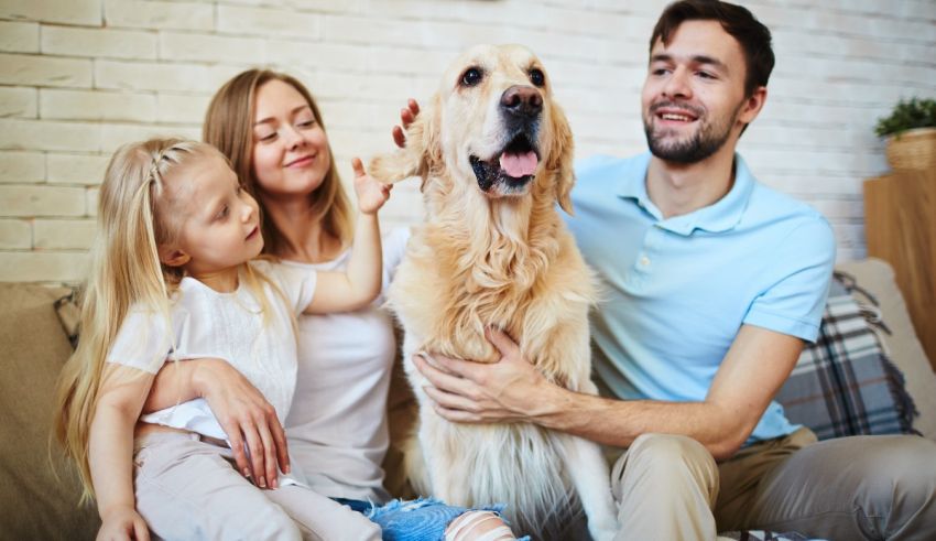 A family sitting on the couch with their dog.
