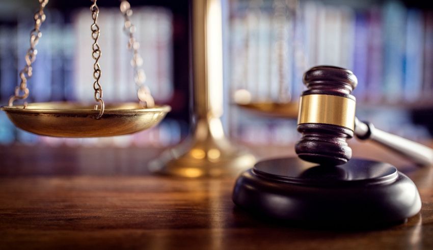 A judge's gavel and scales on a wooden table.