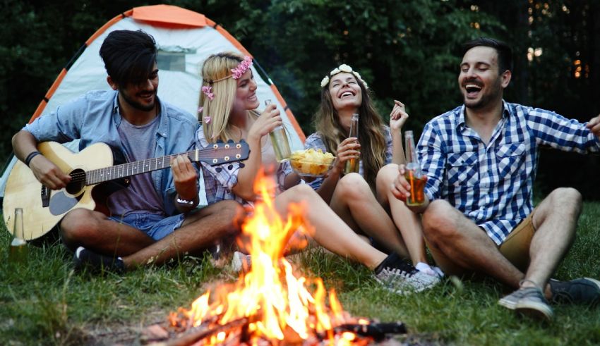 A group of friends sitting around a campfire with guitars.