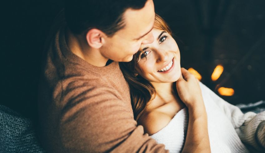 A man and woman hugging while sitting on a couch.