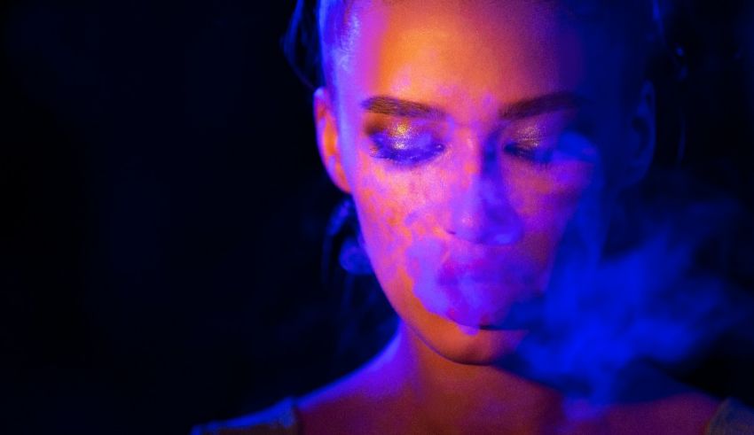 A woman smokes a cigarette in a dark room.