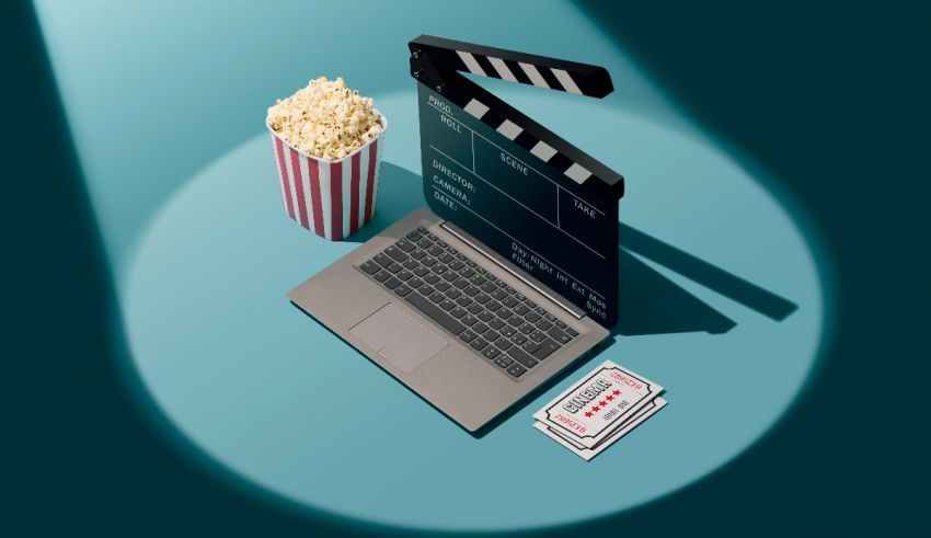 A laptop, movie clapper and popcorn on a blue background.