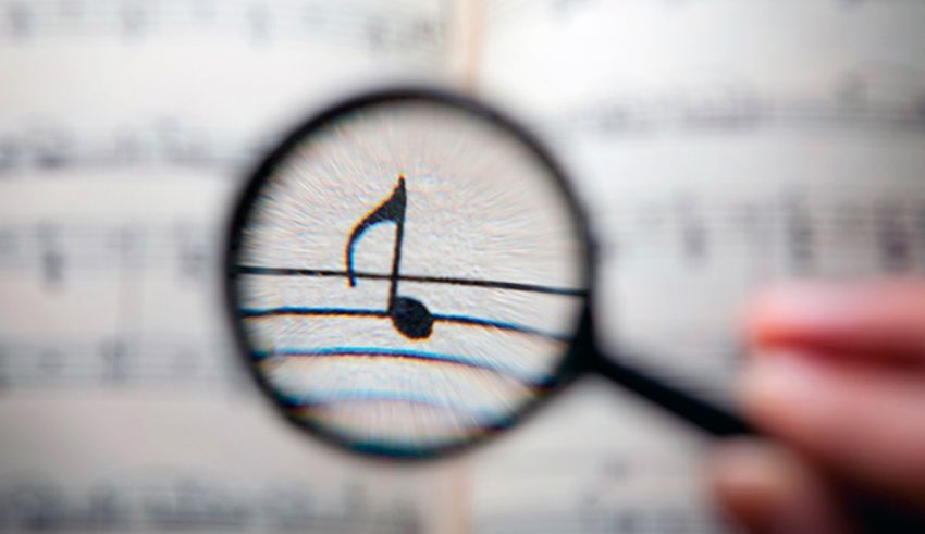 A person is holding a magnifying glass over a sheet of music.