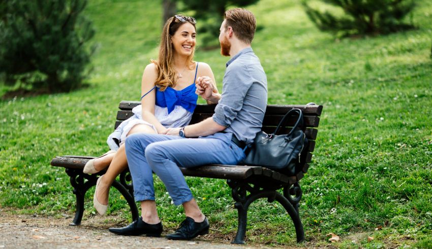 A man and woman sitting on a bench in a park.