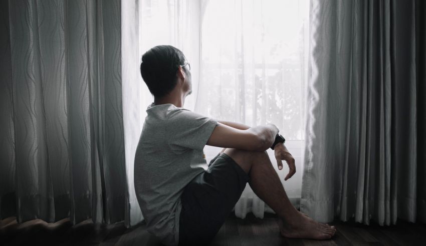 A man sitting on the floor in front of a window.