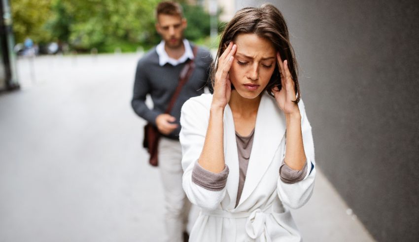 A woman is holding her head while a man is walking down the street.