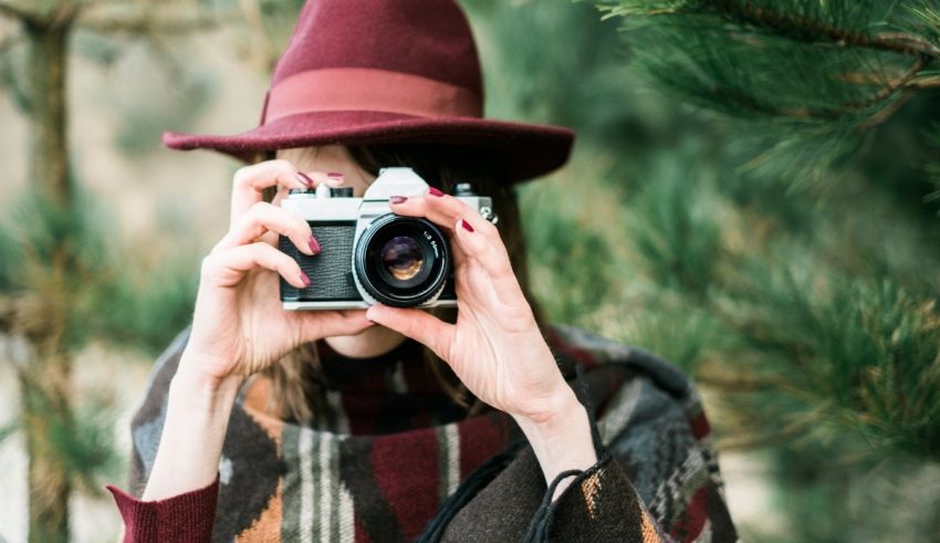 A woman in a hat taking a picture with a camera.