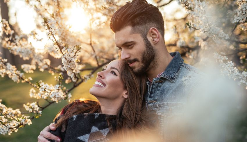 A couple embracing in front of a blossoming tree.