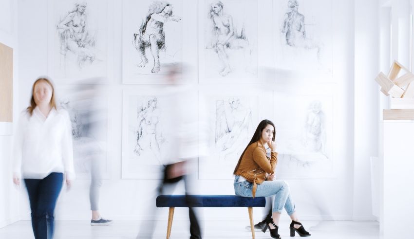 A group of people sitting on a bench in an art gallery.