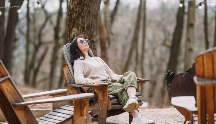Woman relaxing in adirondack chairs in the woods.