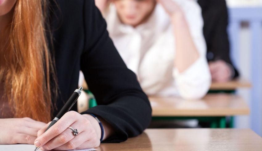 A woman writing on a piece of paper in a classroom.