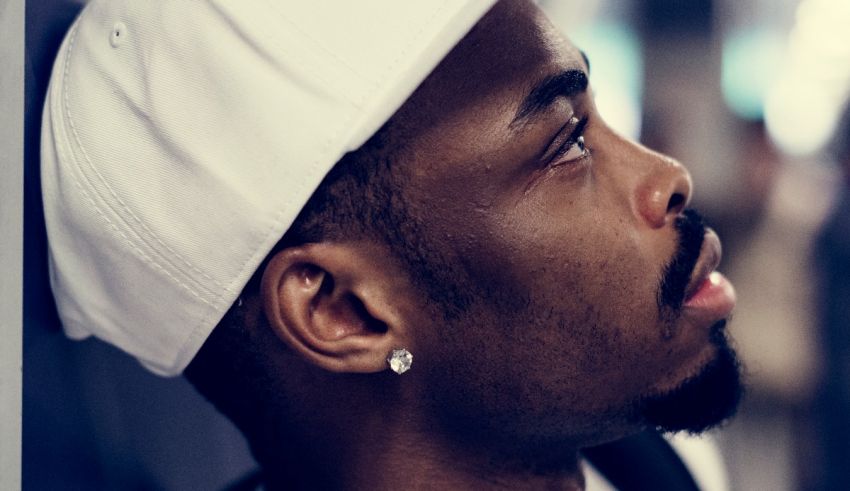 A man in a white hat with ear piercings.