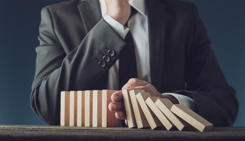A businessman in a suit is playing dominoes with wooden blocks.