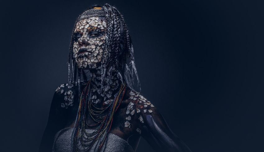 A woman with a headdress and jewelry on a dark background.