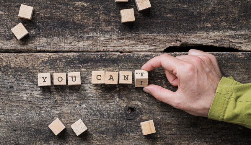 A person is holding wooden cubes that spell out the word you can.