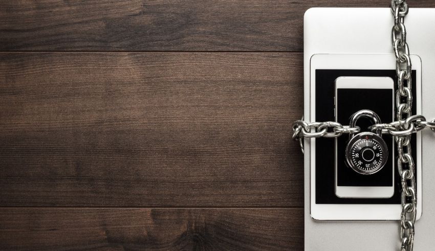 A laptop is chained to a wooden table with a padlock.