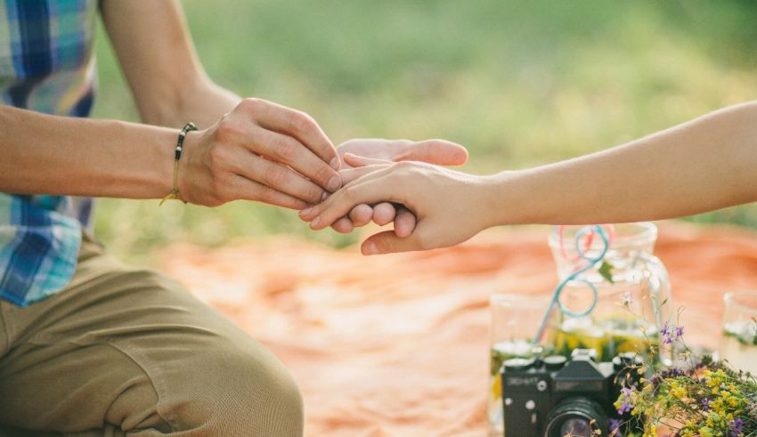A man and woman putting their hands together on a picnic blanket.