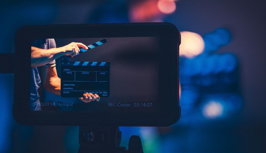 A person holding a clapper in front of a camera.