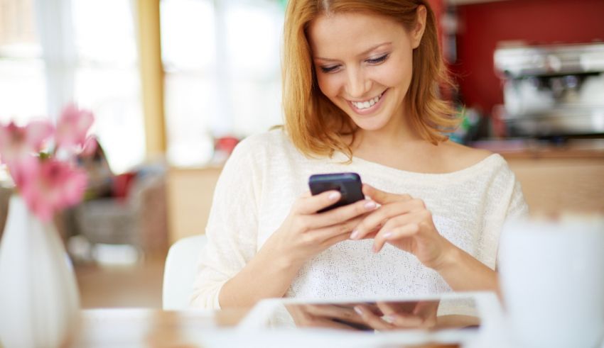 A woman sitting at a table looking at her cell phone.