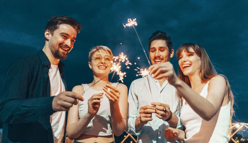 A group of friends holding sparklers at night.